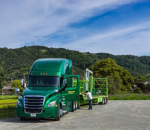 A person working alongside a green truck.