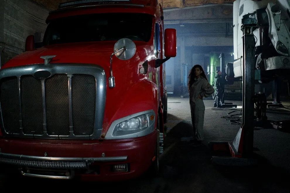 Woman wearing jumpsuit standing next to a red truck