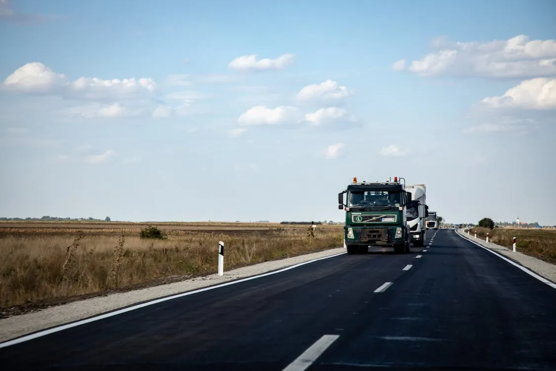 A dark colored truck driving on an open road.