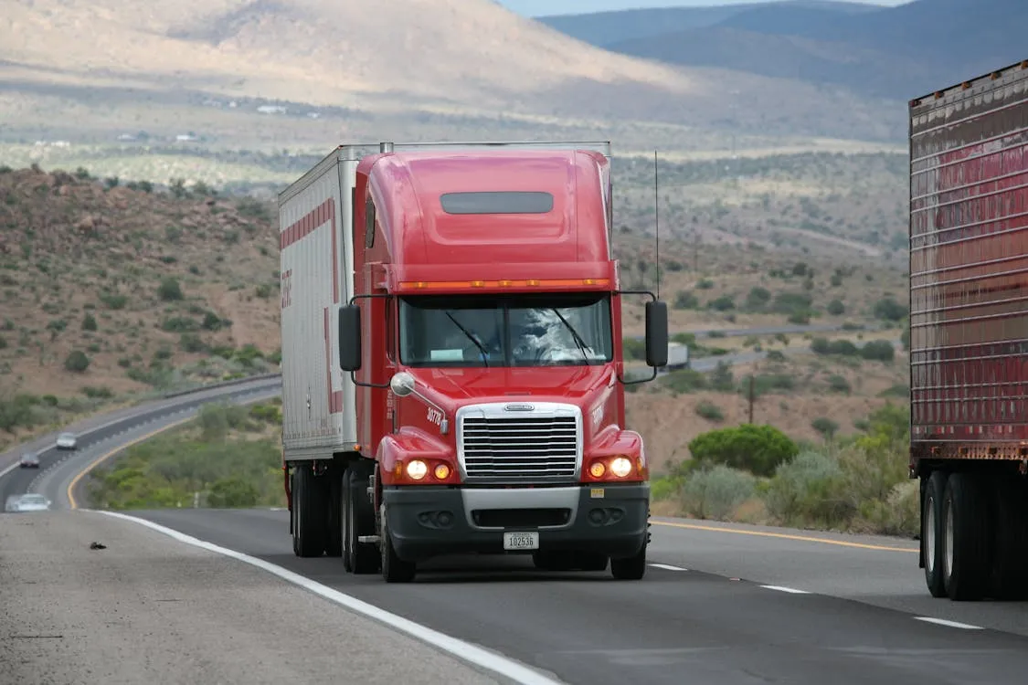 A red and white truck driving on the freeway. 