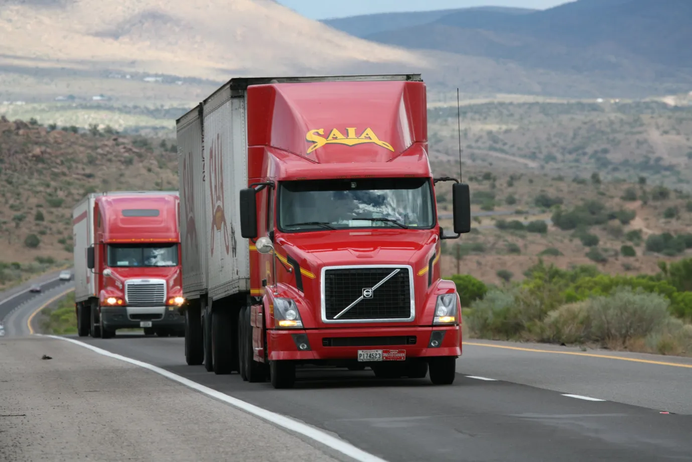 Two red 12-wheeler trucks on the highway during daytime