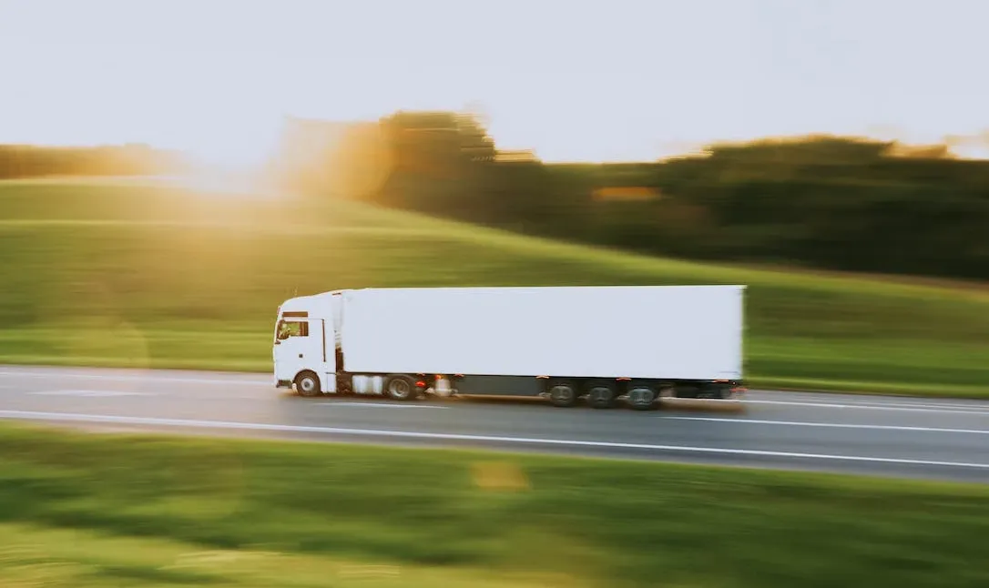 A 10-wheeler white truck in motion on a smooth road
