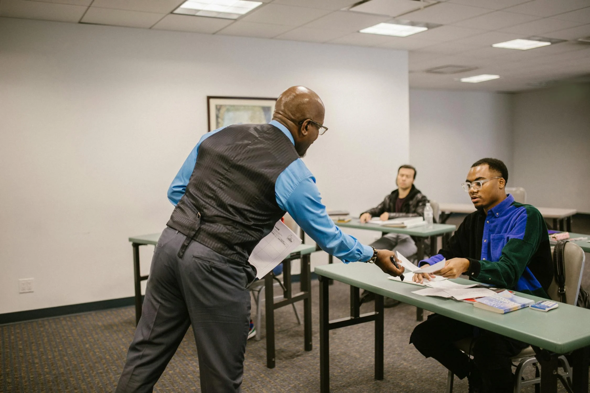 An invigilator handing a document to a student during CDL test