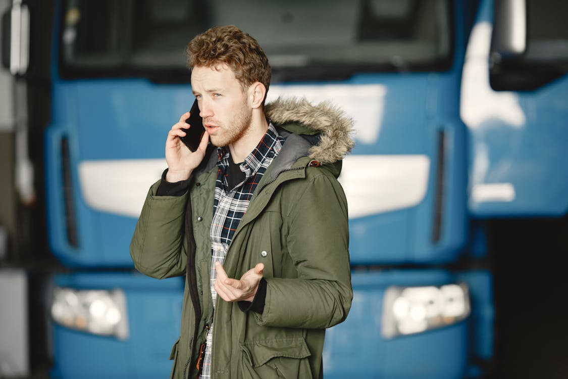 A commercial driver talking on the phone in front of their truck