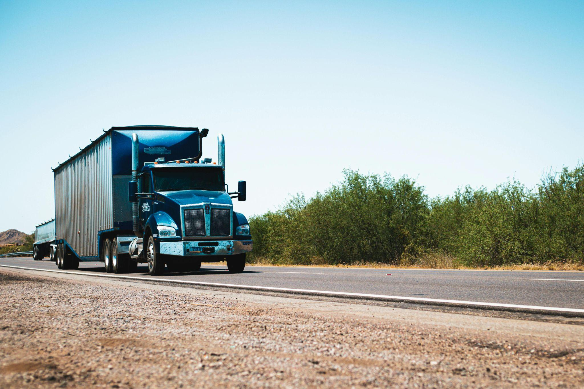 A black truck driving down a road