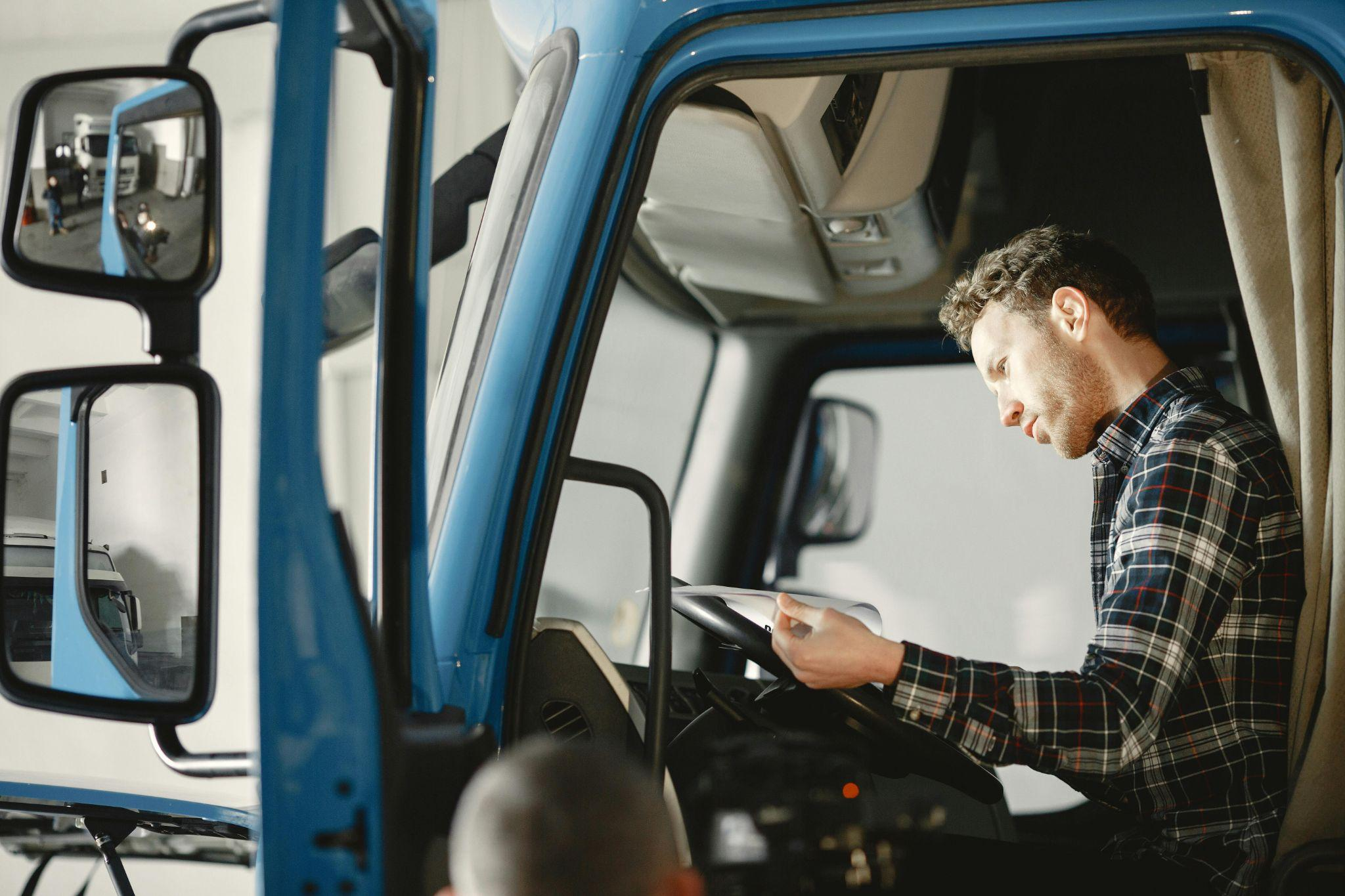A person inside a truck, reading from a manual
